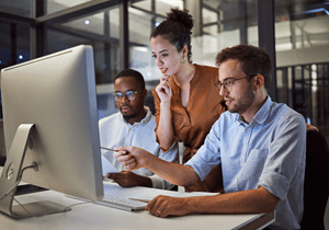 Three professionals viewing a computer screen.